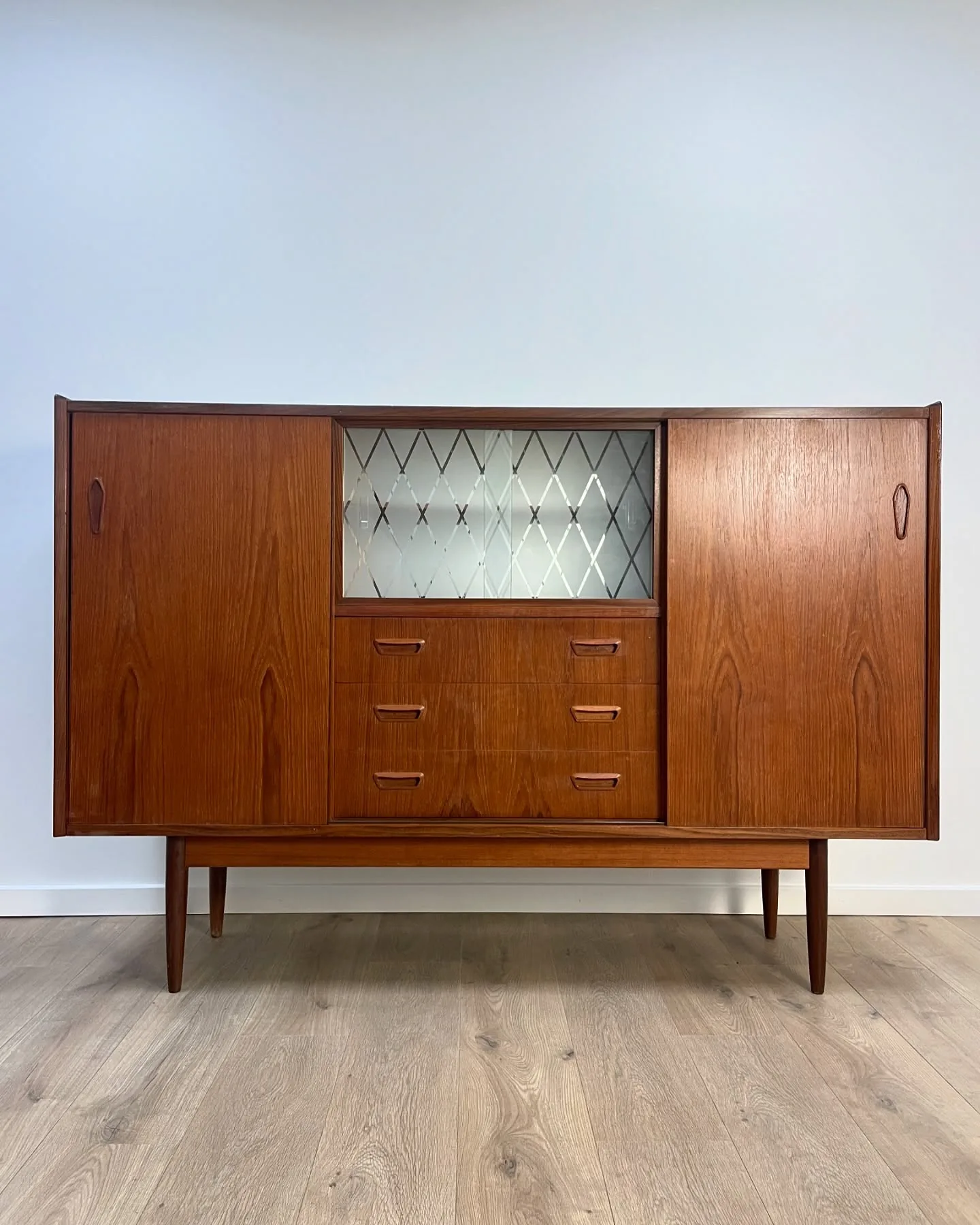 Teak skænk

Skydelåger hvor bag hylder og skuffer. Glaslåger med bar bag.
Sort bemalet to…